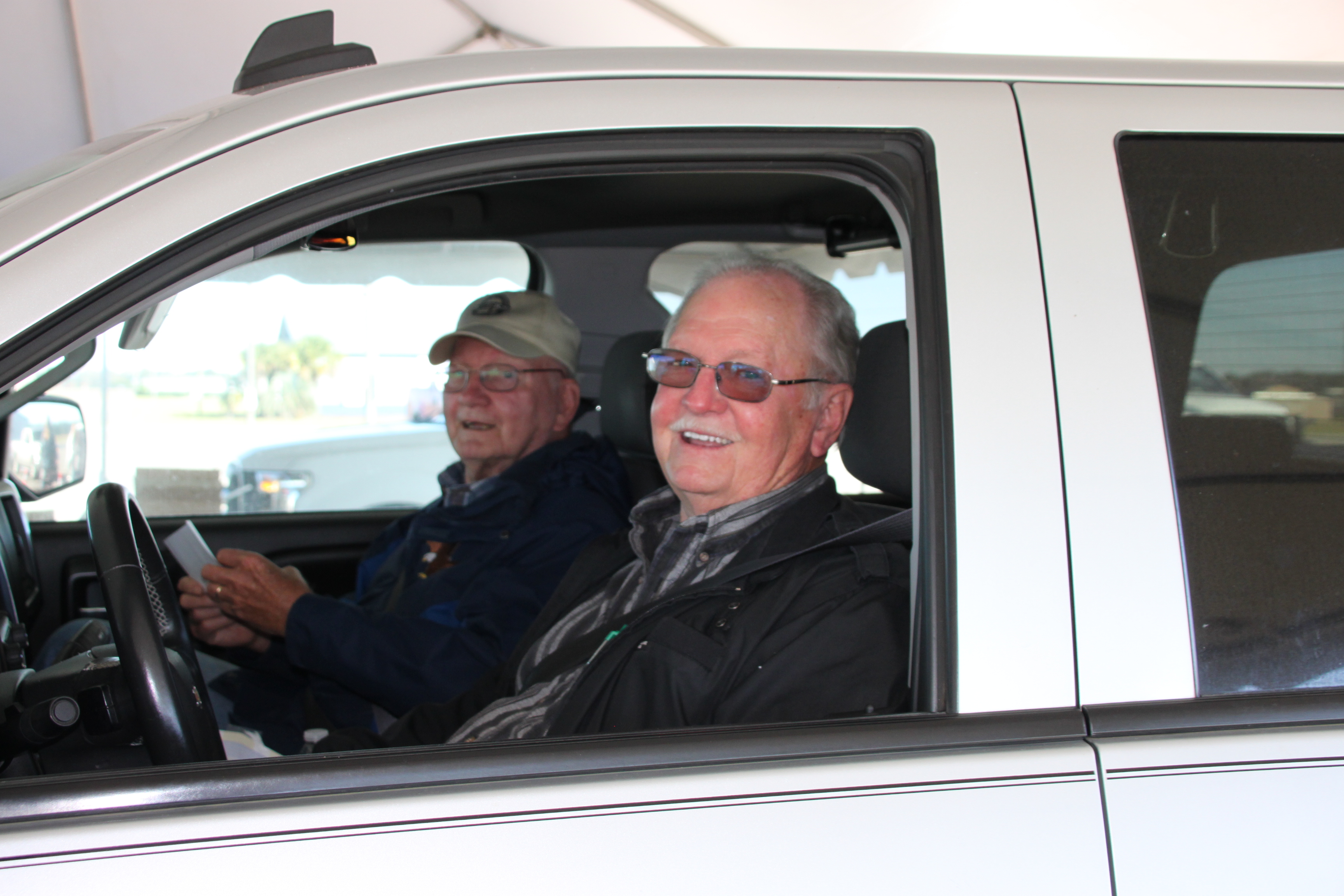Two EMC members inside of a truck, smiling at the camera through the driver's side window